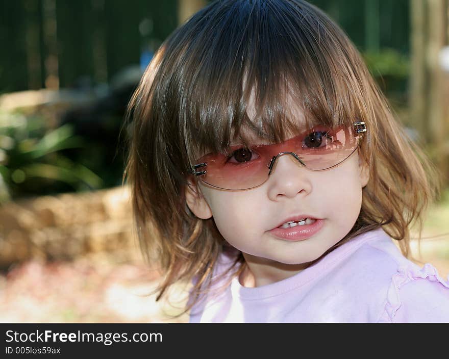 Small child wearing sunglasses while playing outstide. Small child wearing sunglasses while playing outstide