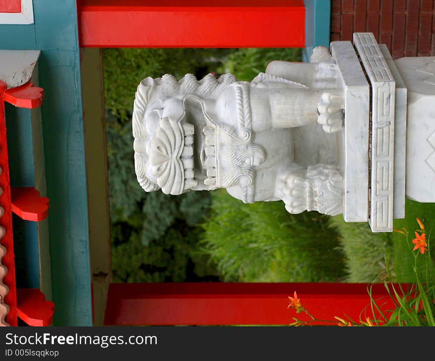 Marble lion figure amidst Chinese-style architectural elements in red and cyan. Marble lion figure amidst Chinese-style architectural elements in red and cyan.