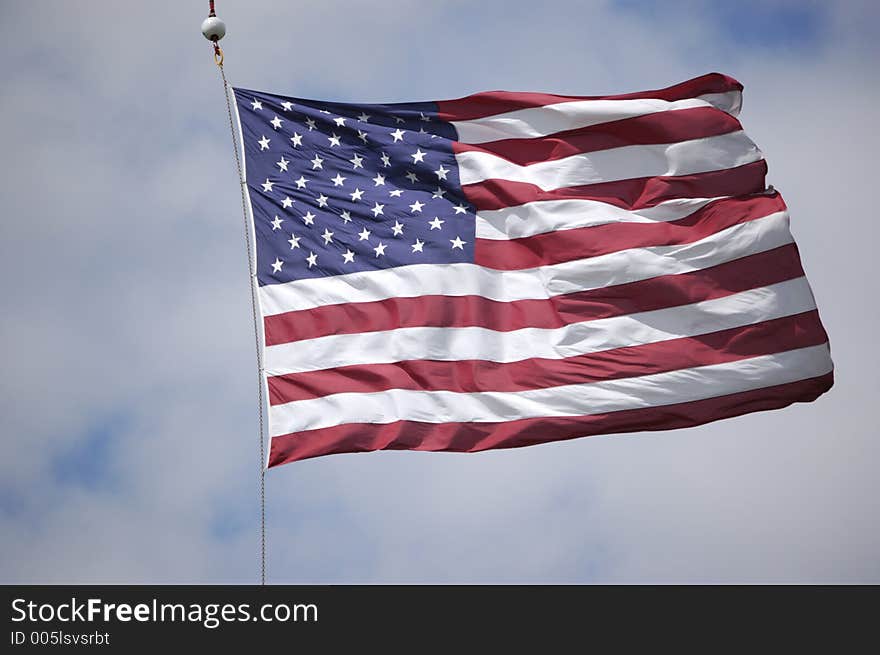 A large United States flag waves in the wind as it is suspended from a crane at a veteran's flag memorial event. A large United States flag waves in the wind as it is suspended from a crane at a veteran's flag memorial event.