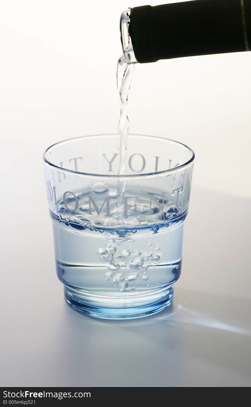 Glass with water being poured into from a wine bottle. Glass with water being poured into from a wine bottle.