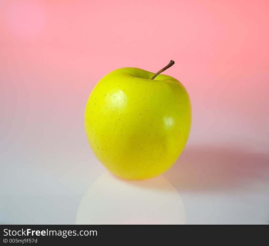 A yellow apple isolated in light pink background