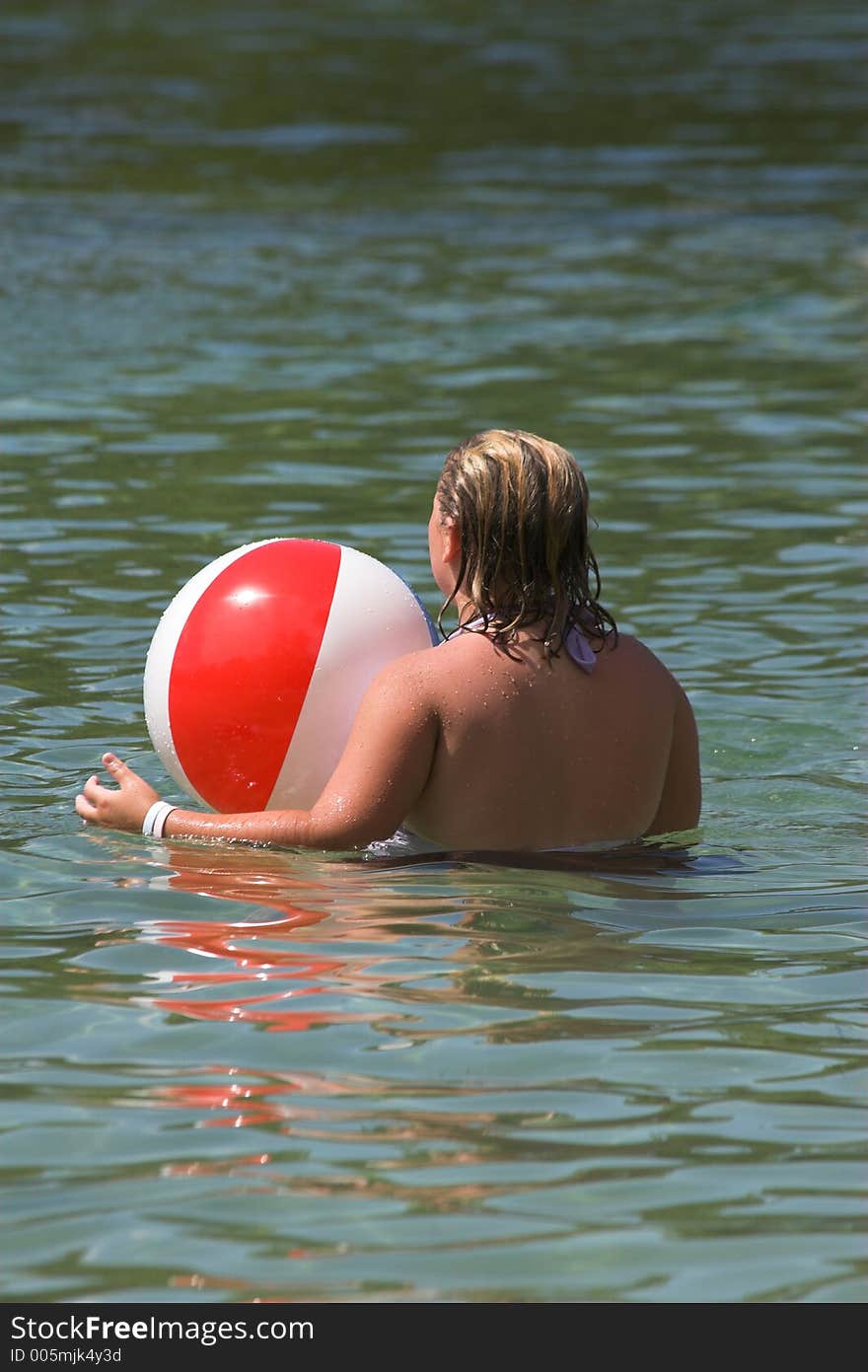 Girl playing in water at local lake with beach ball. Girl playing in water at local lake with beach ball