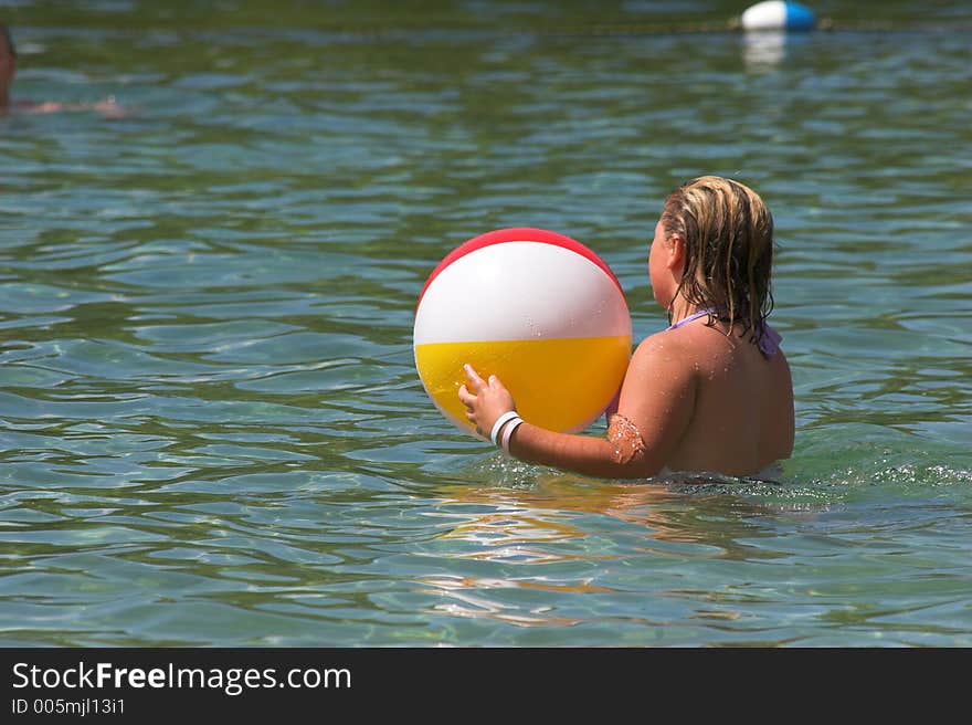 Little girl playing in water with beach ball. Little girl playing in water with beach ball