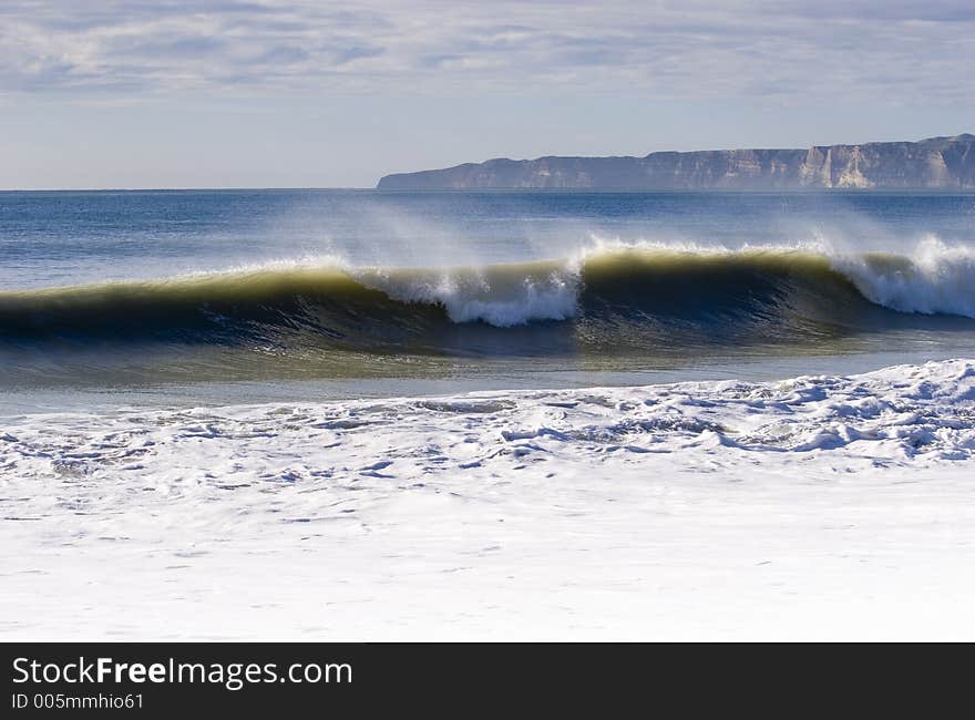 Waves breaking with Cape Kidnappers in Background. Hawke's Bay, New Zealand