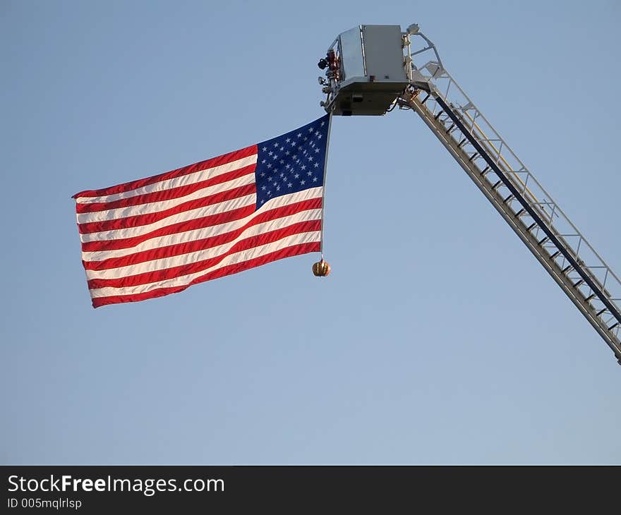 The American flag attached to a fire engine ladder waves straight out. The American flag attached to a fire engine ladder waves straight out.