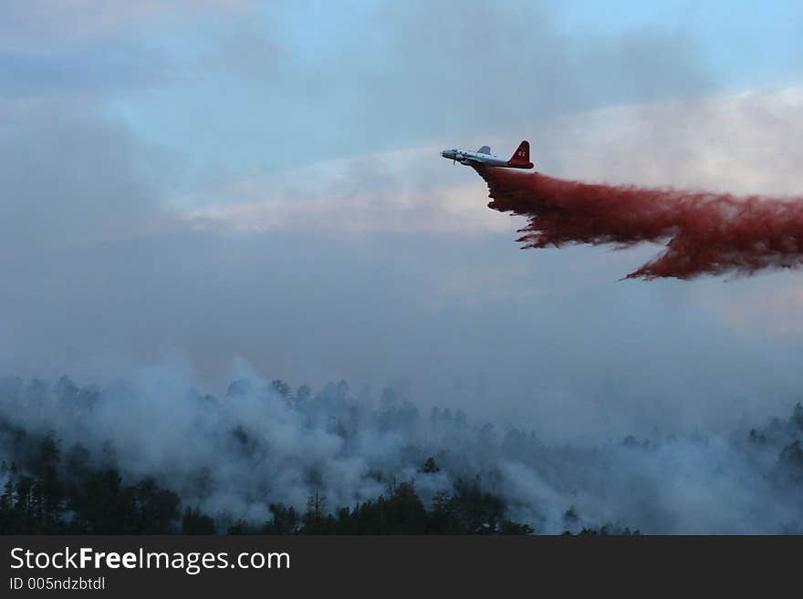 Slurry bomber dropping retardant on a forest fire