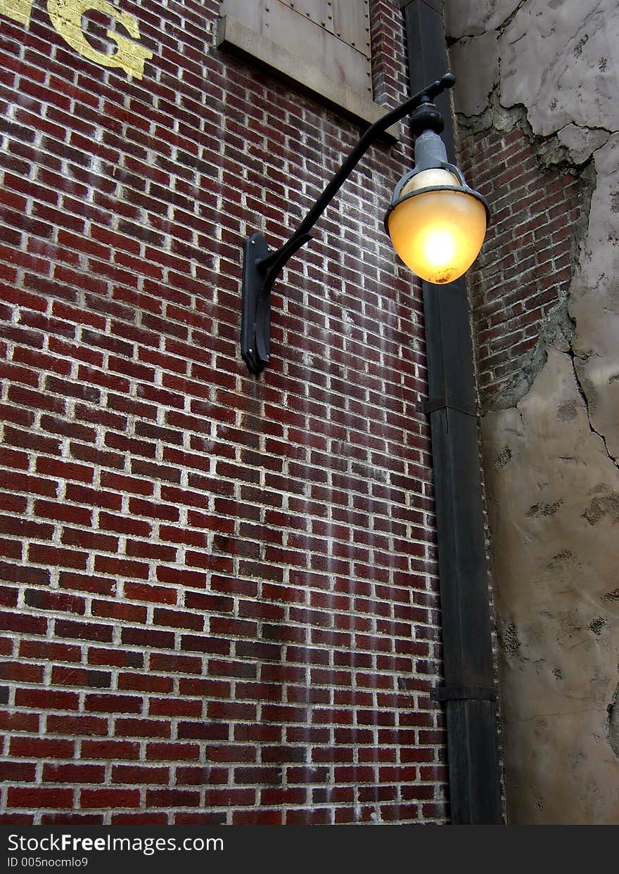A photograph of an old section of town down a back alley with the street light just coming on at dusk. A photograph of an old section of town down a back alley with the street light just coming on at dusk
