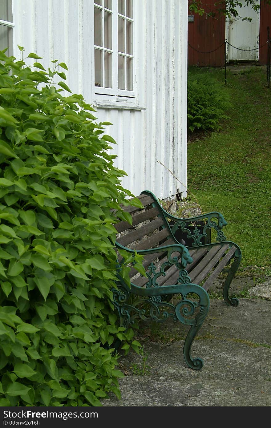 Iron and wooden bench on the outside of an old wooden house. Iron and wooden bench on the outside of an old wooden house