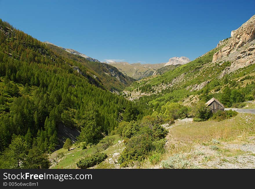 A picturesque valley with wooded sides on sunny day. There is a shed in the foreground.