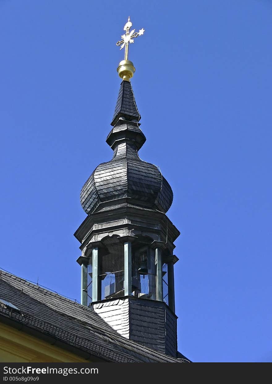 Chapel tower with church bell and golden cross on the rooftop