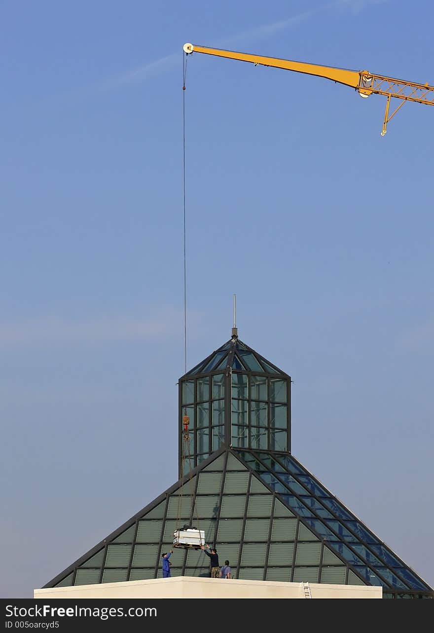 Yellow crane lifting a pallet on a roof