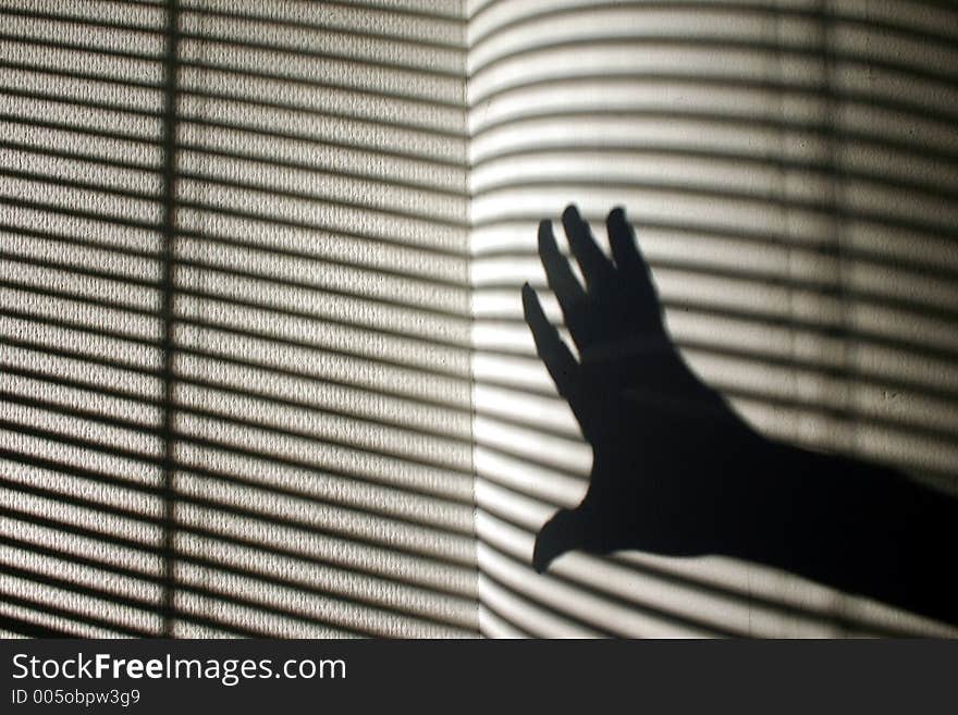 Shade of a hand with striped wall in the background