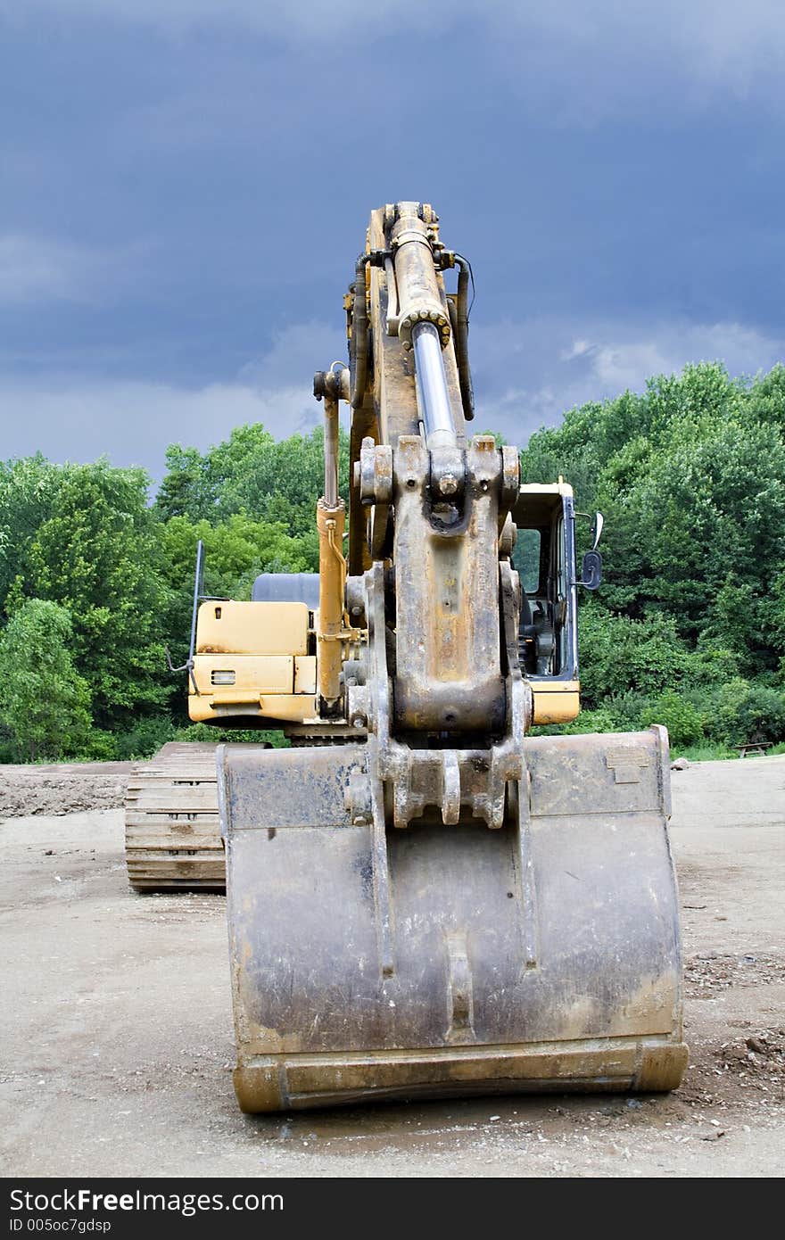 A Backhoe parked at the construction scene - storm brewing - cloudy dramatic sky. A Backhoe parked at the construction scene - storm brewing - cloudy dramatic sky.