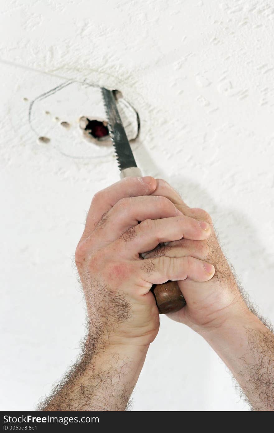 An electrician with using a saw to cut a hole in the ceiling to put a fan box. Work is being performed by a licensed master electrician. An electrician with using a saw to cut a hole in the ceiling to put a fan box. Work is being performed by a licensed master electrician.