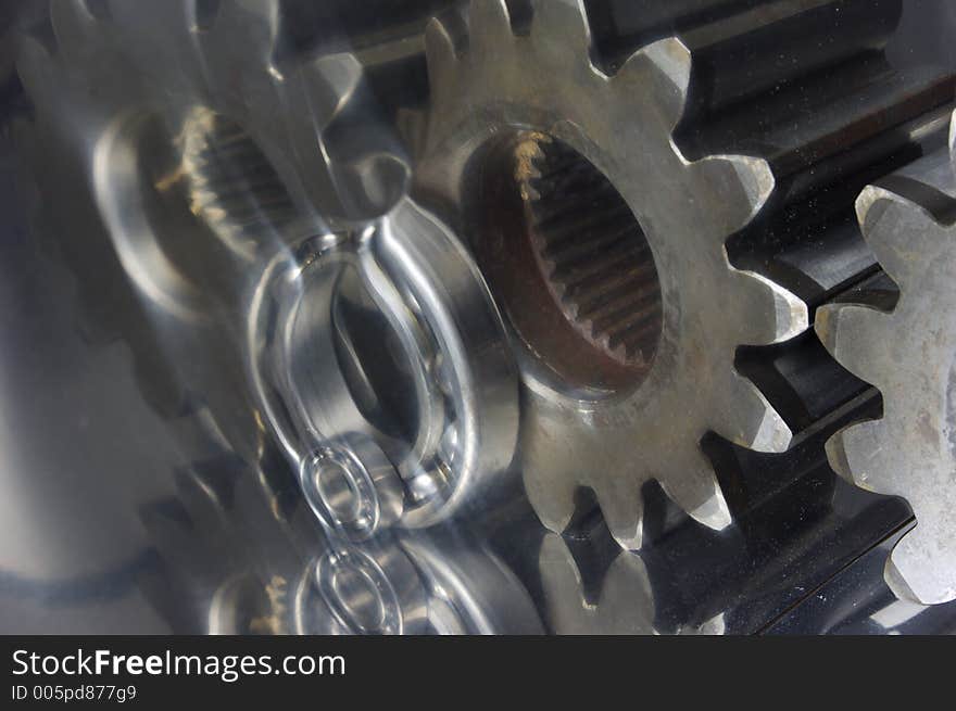 Gears, cogs heavily reflecting in curvrd titanium, distorted-reflection. Gears, cogs heavily reflecting in curvrd titanium, distorted-reflection