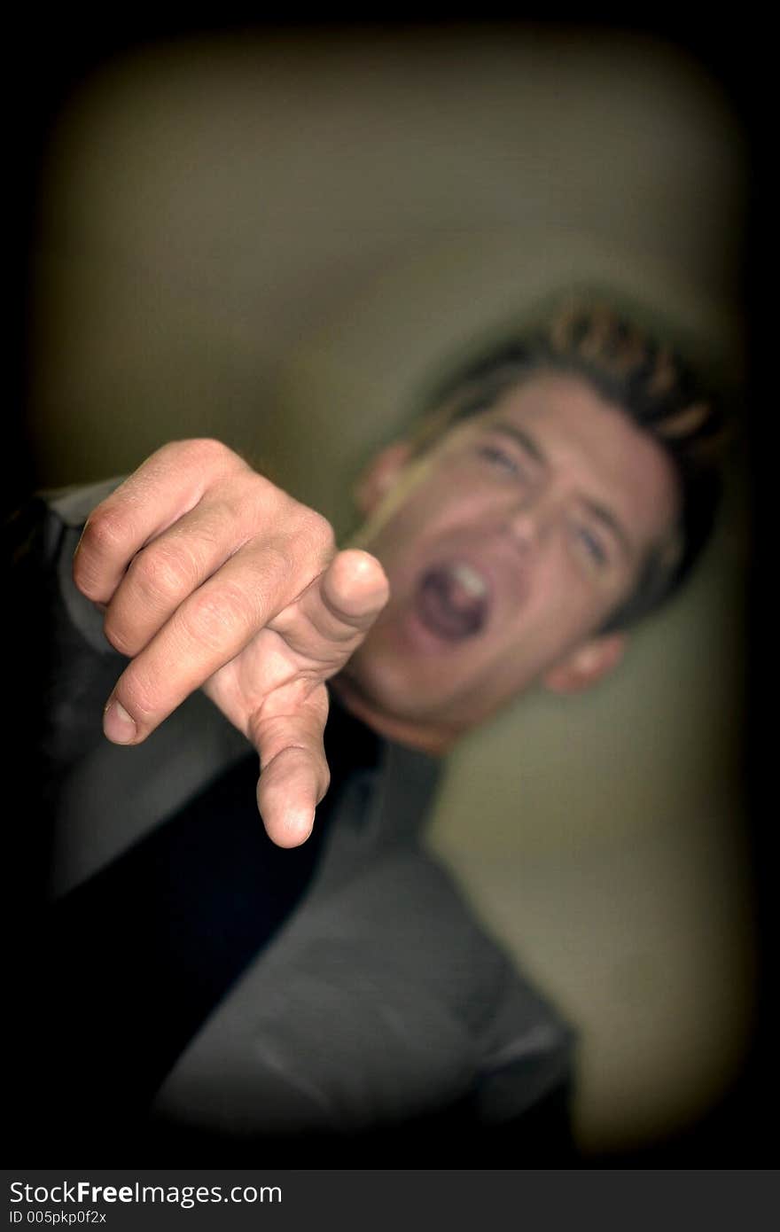 Business Man points with look of disbelief on his face with a gray shirt, black tie, and tan background