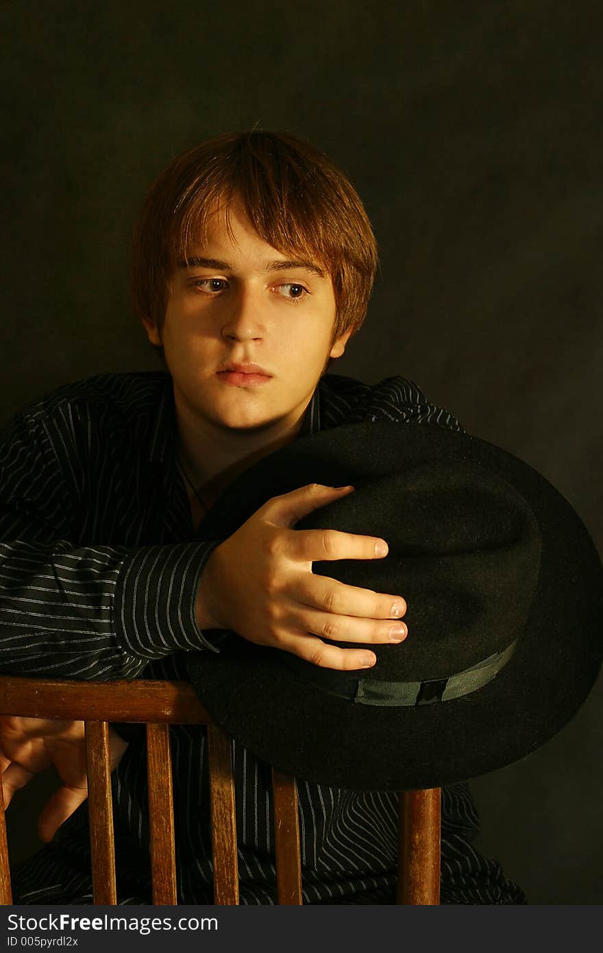 Portrait of the young man on a black background. In a hand a hat. Portrait of the young man on a black background. In a hand a hat.