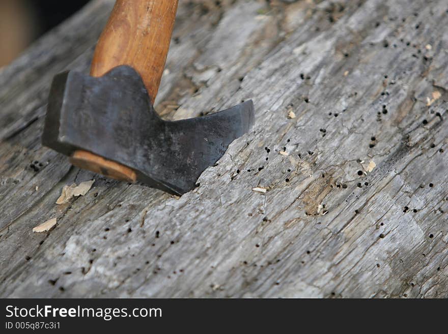 An axe buried into a piece of lumber, waiting to be carved into shape by carpenter. An axe buried into a piece of lumber, waiting to be carved into shape by carpenter