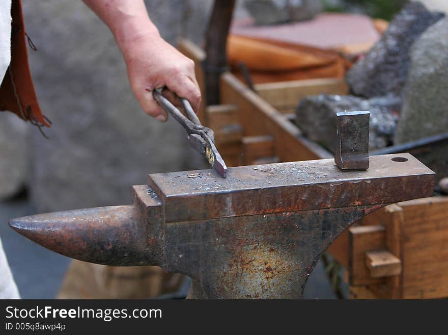 A craftsman/blacksmith working metal the oldfashioned way, with hammer and anvil and open fire. A craftsman/blacksmith working metal the oldfashioned way, with hammer and anvil and open fire