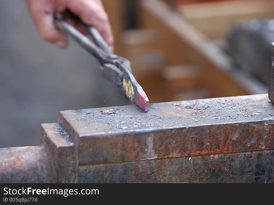 A craftsman/blacksmith working metal the oldfashioned way, with hammer and anvil and open fire. A craftsman/blacksmith working metal the oldfashioned way, with hammer and anvil and open fire