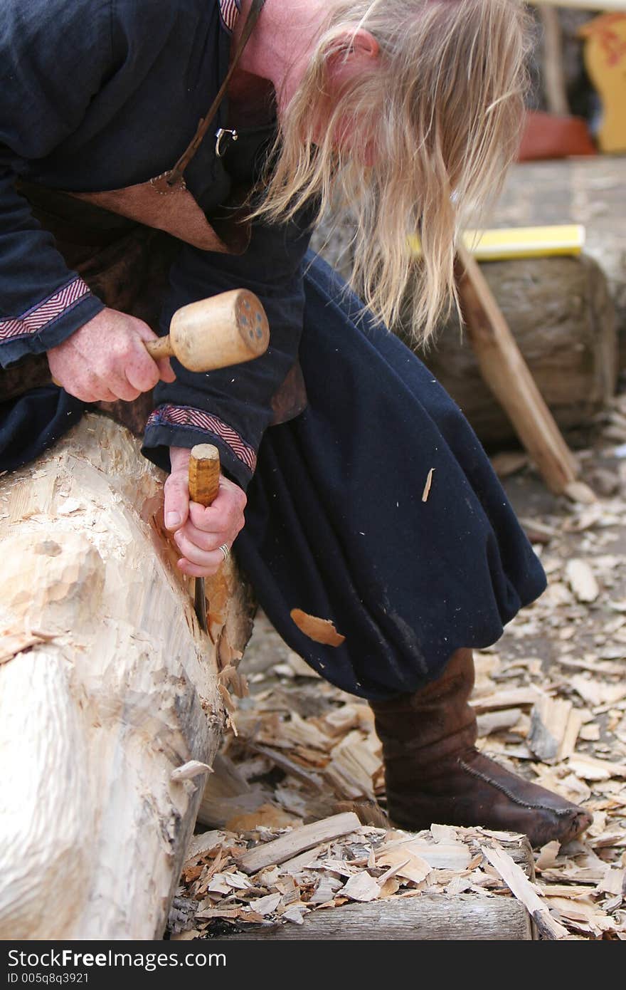 A craftsman working wood the oldfashioned way, chipping away and molding a figure out of a big piece of wood. A craftsman working wood the oldfashioned way, chipping away and molding a figure out of a big piece of wood