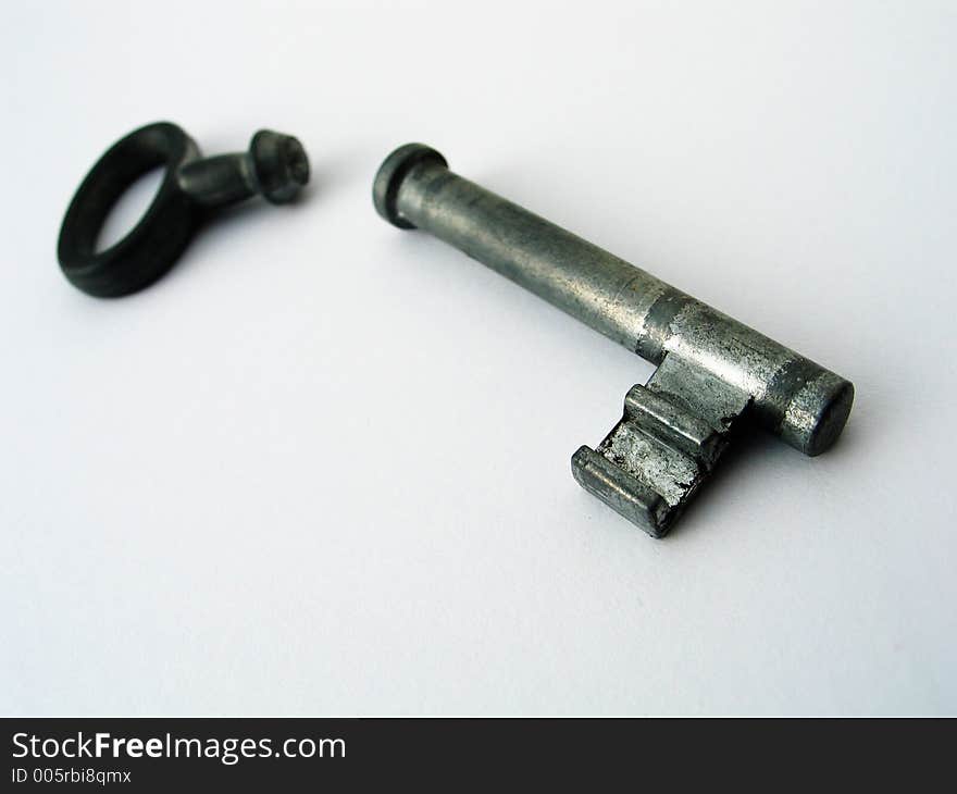 A broken metal key on white background. Low DOF. A broken metal key on white background. Low DOF.