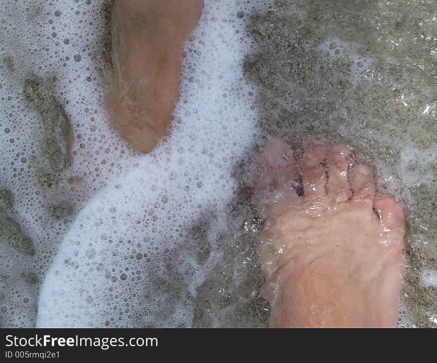 Couples`s feet in water waves