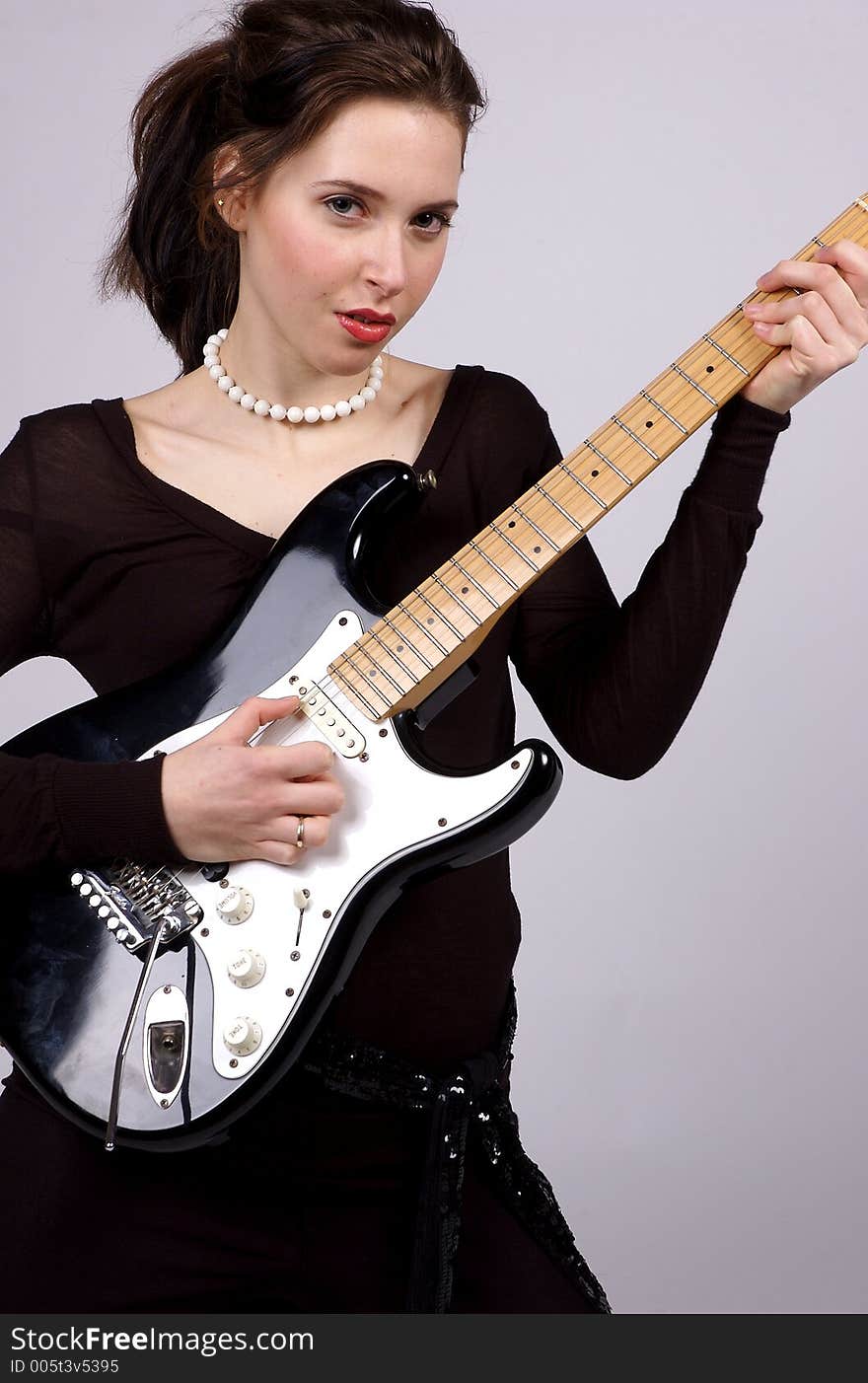 A Young woman playing an electric guitar, wearing black and looking straight at the camera. A Young woman playing an electric guitar, wearing black and looking straight at the camera