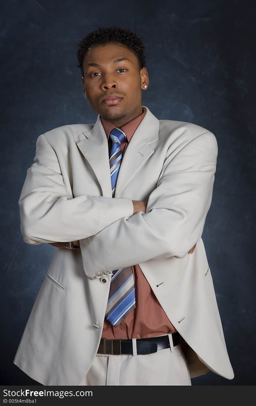 A man in a suit, standing with his arms folded. A man in a suit, standing with his arms folded