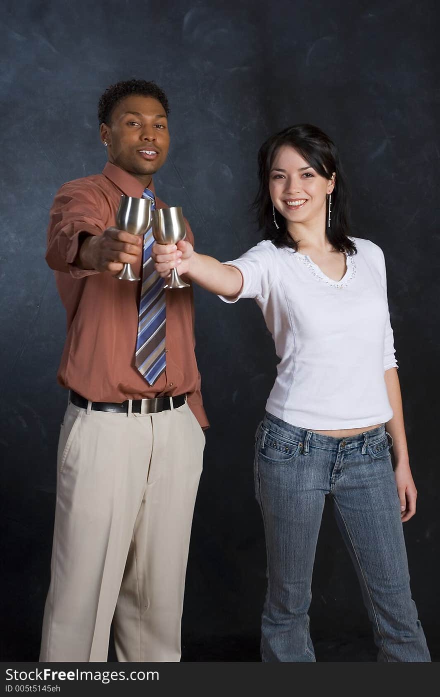 A man and woman raising their cups and smiling. A man and woman raising their cups and smiling