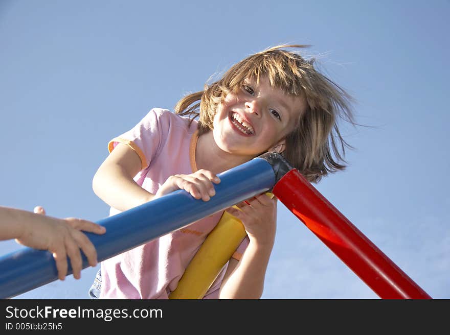 Young girl playing on a climbing pole - looking down to the photografer. Young girl playing on a climbing pole - looking down to the photografer