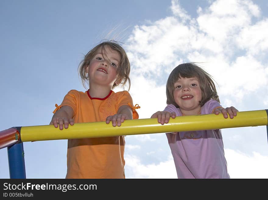 Twins on a climbing pole - looking down to the photografer. Twins on a climbing pole - looking down to the photografer