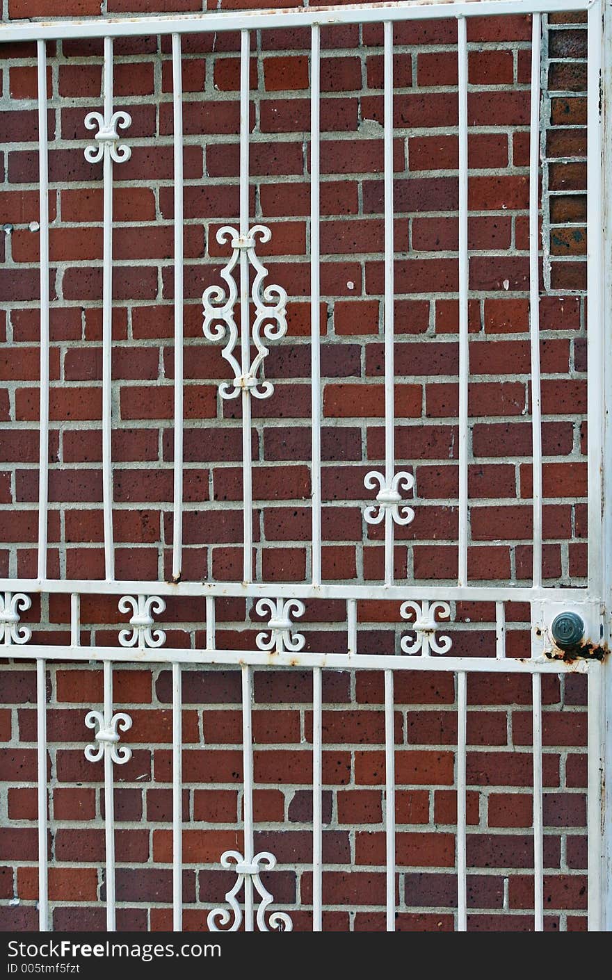 Ornate white iron gate against brick wall. Ornate white iron gate against brick wall