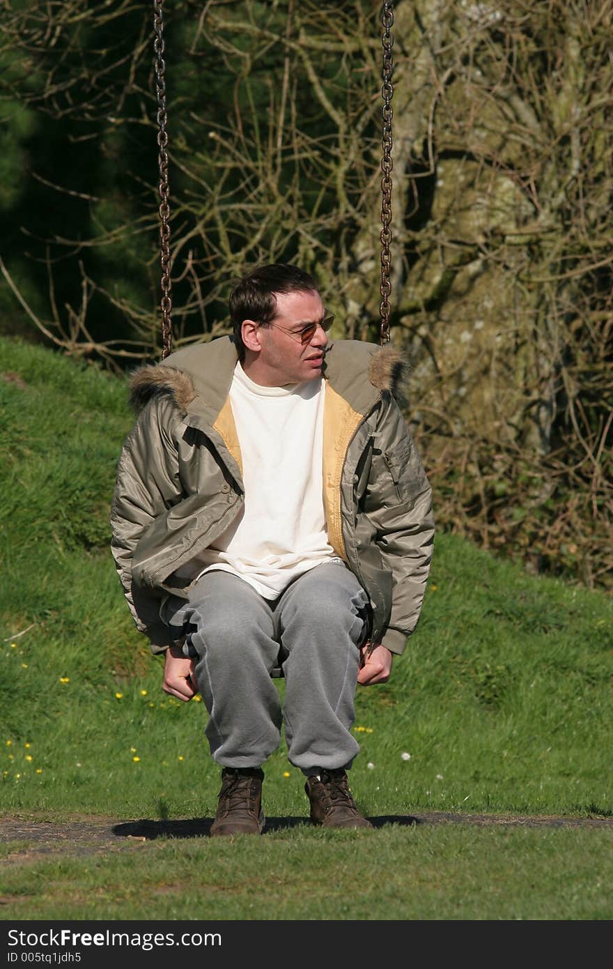 Middle aged man sitting on a swing. Middle aged man sitting on a swing.