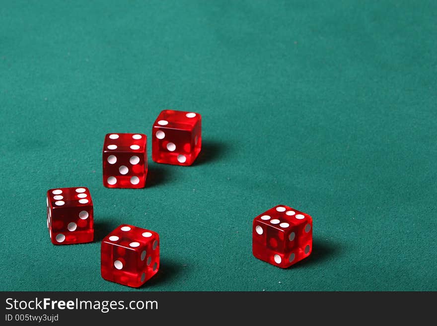 Dices being thrown in a craps game, or yatzee or any kind of dice involved game, Dices are a clear red color on a green felt table. Dices being thrown in a craps game, or yatzee or any kind of dice involved game, Dices are a clear red color on a green felt table