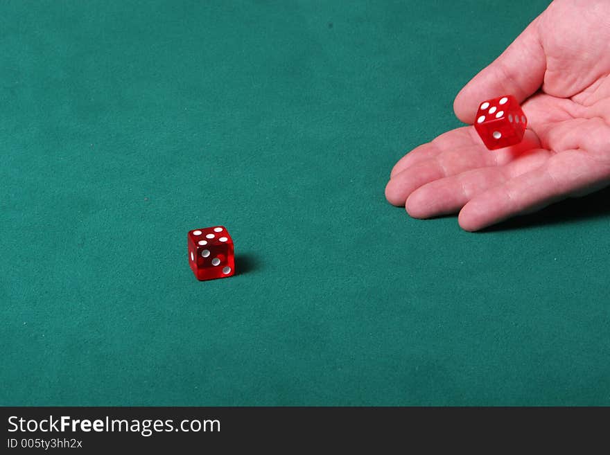 Dices being thrown in a craps game, or yatzee or any kind of dice involved game, Dices are a clear red color on a green felt table. Dices being thrown in a craps game, or yatzee or any kind of dice involved game, Dices are a clear red color on a green felt table