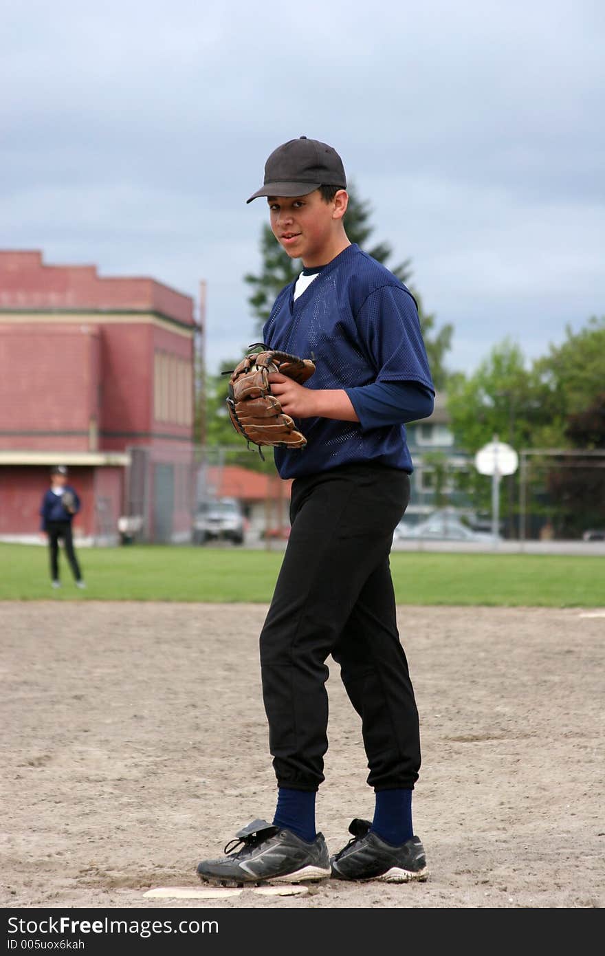 A teenage boy waiting for the play at first base. A teenage boy waiting for the play at first base.