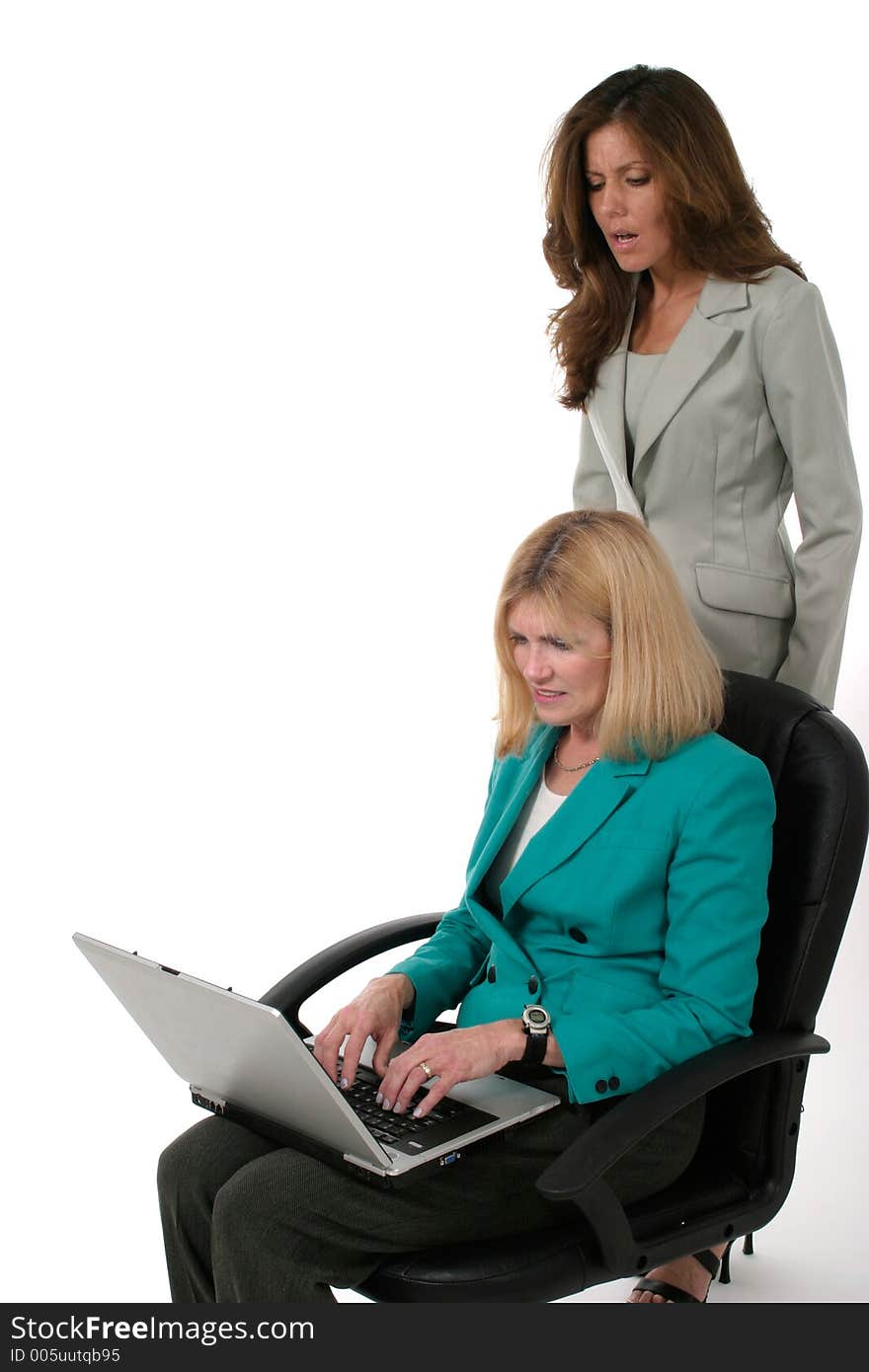 Attractive and beautiful two business woman team working at a laptop computer together. One team member is looking over the shoulder of the other. Attractive and beautiful two business woman team working at a laptop computer together. One team member is looking over the shoulder of the other.