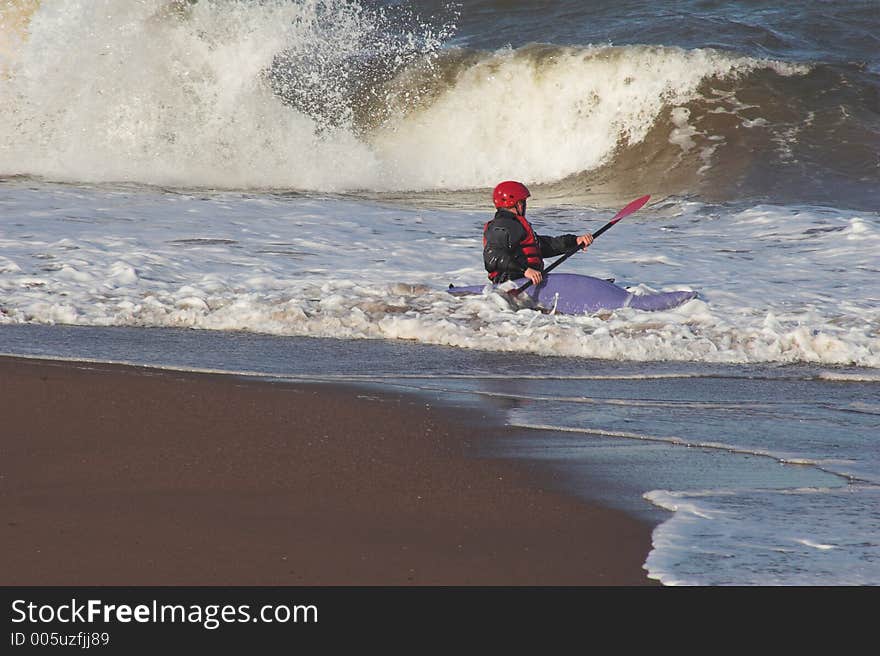 Man in blue canoe, on edge of surf. Man in blue canoe, on edge of surf