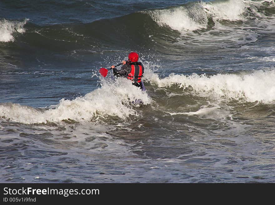 Man rowing canoe into surf. Man rowing canoe into surf