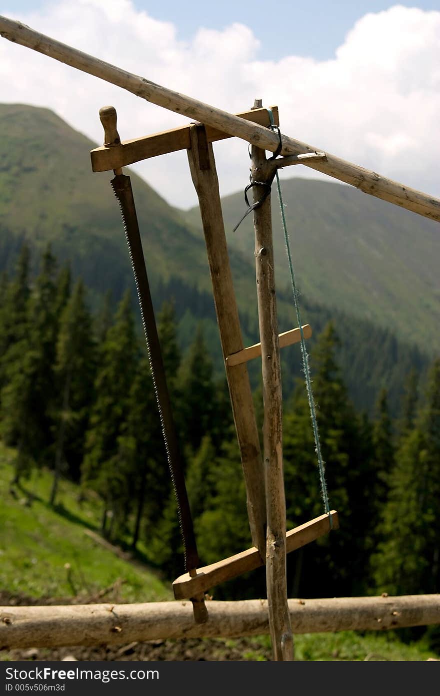 Old saw hanged on the fence angainst the forest background. Old saw hanged on the fence angainst the forest background