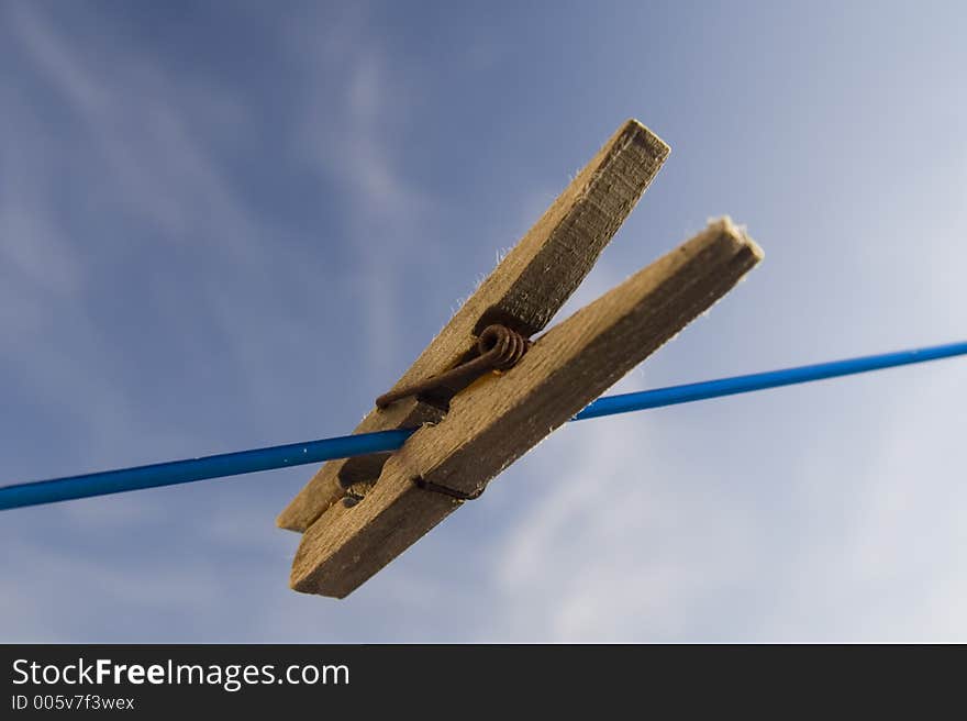 Lonely clothes peg on blue cord of rotary clothes line. Lonely clothes peg on blue cord of rotary clothes line.