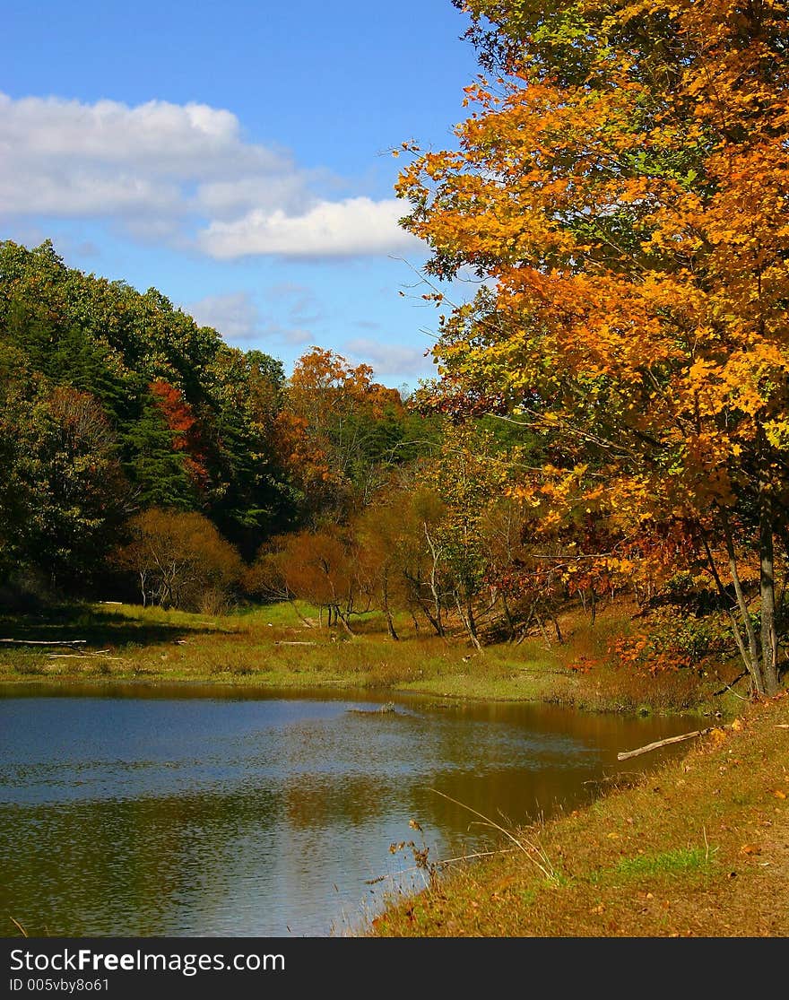 Beautiful blue sky with white clouds, colorful foliage, trees, and lake. Beautiful blue sky with white clouds, colorful foliage, trees, and lake.