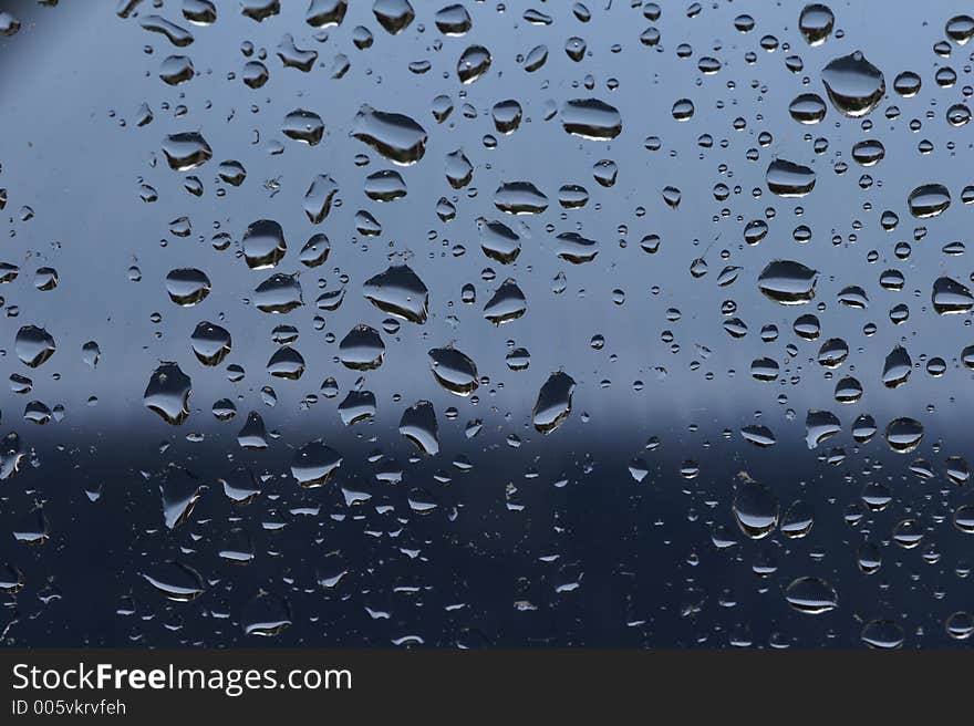 Raindrops at a window - blue background. Raindrops at a window - blue background