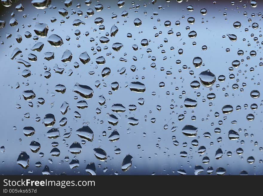 Raindrops at a window - blue background. Raindrops at a window - blue background