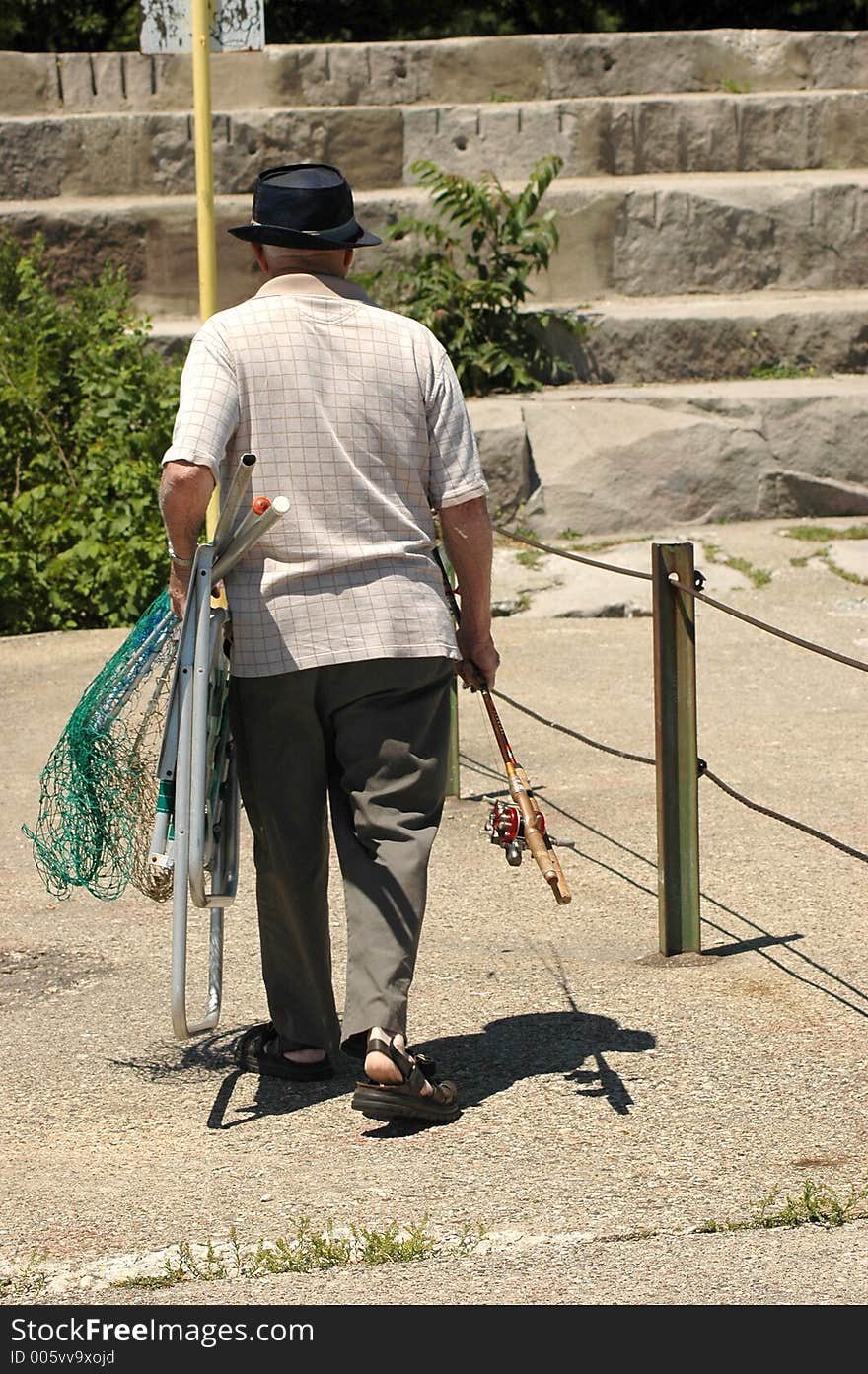 Elderly man leaving after fishing. Elderly man leaving after fishing