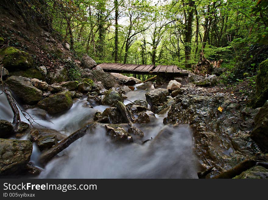 A small wooden bridge across a mountain torrent. A small wooden bridge across a mountain torrent