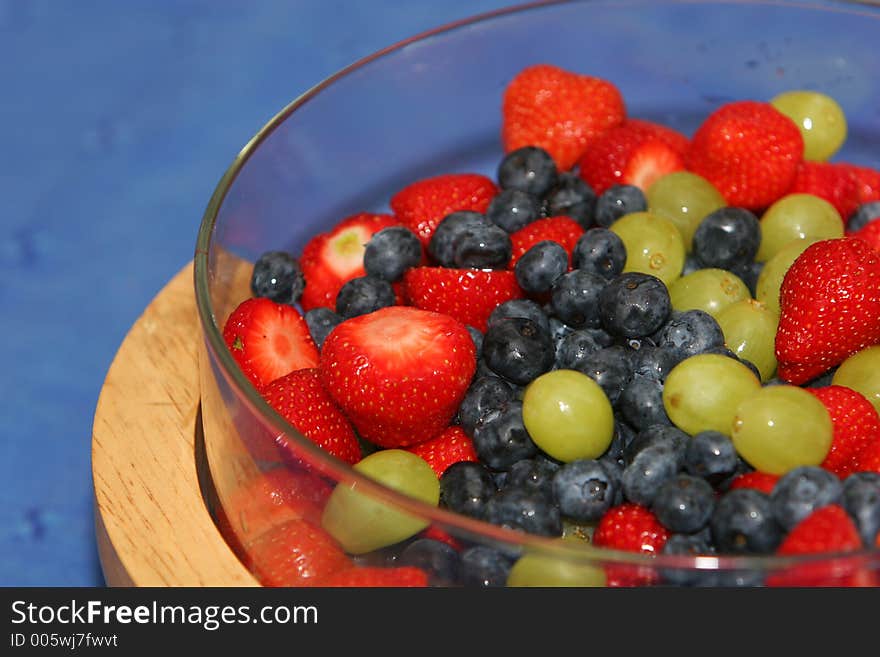 A dish of fresh berries, strawberries, blueberries, grapes and whipped cream. A dish of fresh berries, strawberries, blueberries, grapes and whipped cream.