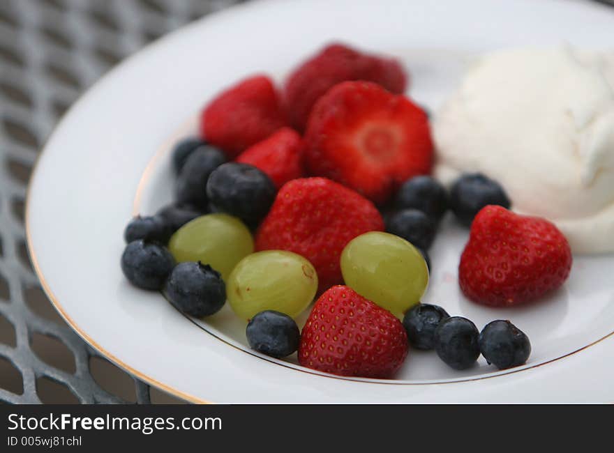 A dish of fresh berries, strawberries, blueberries, grapes and whipped cream. A dish of fresh berries, strawberries, blueberries, grapes and whipped cream.