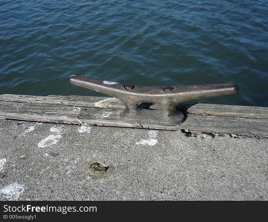 A metal boat mooring attached to a wooden rail. A metal boat mooring attached to a wooden rail